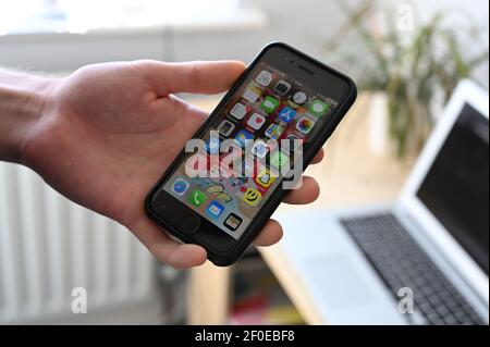 Gros plan d'un jeune homme tenant un iPhone Apple se affichant des applications. Banque D'Images