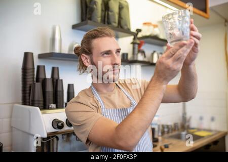 Homme attentif regardant le verre dans les mains levées Banque D'Images