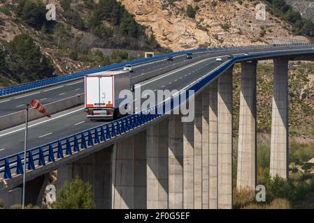 Camion réfrigéré roulant au-dessus d'un long pont et à côté d'une chaussette à vent. Banque D'Images