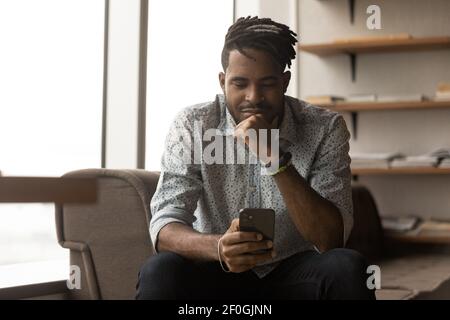 Gros plan un homme afro-américain satisfait regardant l'écran du téléphone Banque D'Images