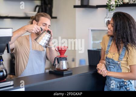 Un barista masculin prépare du café à l'aide d'un plongeur Banque D'Images