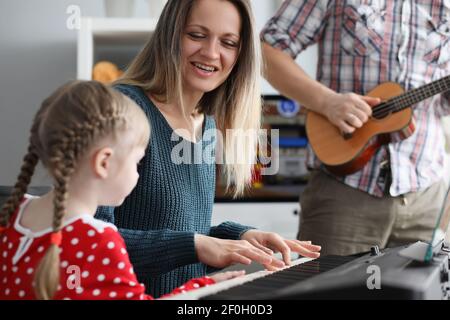 Femme et homme enseignant à la petite fille de jouer de l'instrument de musique Banque D'Images