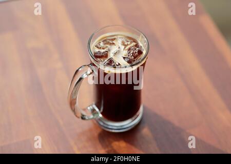 Un verre de boisson froide dans une tasse transparente sur une table en bois Banque D'Images