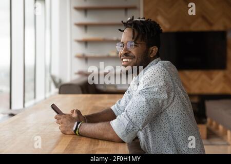 Gros plan souriant homme afro-américain distrait du téléphone Banque D'Images