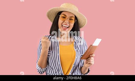 Une femme asiatique qui tient son passeport avec son billet crie oui Banque D'Images