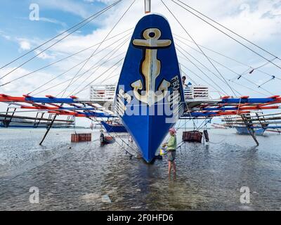 Travaux d'entretien sur un bateau de pêche traditionnel avec des stabilisateurs à Tinoto, un village de pêcheurs de Maasim, dans la province de Sarangani aux Philippines Banque D'Images