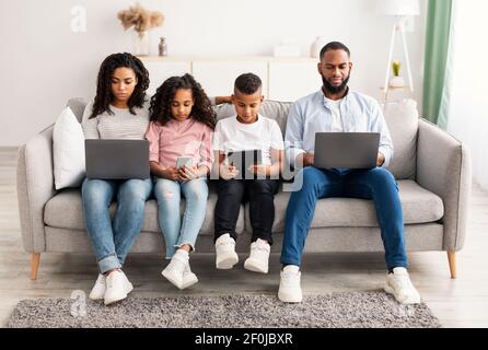 Famille afro-américaine tenant et utilisant des gadgets Banque D'Images