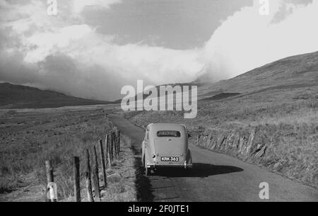 Années 1950, historique, Touring Wales, une voiture de l'époque garée sur une ruelle de campagne sur les contreforts des montagnes de Snowdonia, et une couverture de nuages couvre le paysage lointain. Banque D'Images