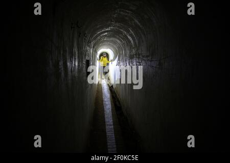 Femme avec un phare debout dans le système souterrain historique italien à Unska Kolisevka, Slovénie Banque D'Images