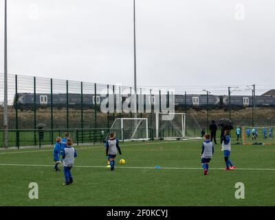 Kilwinning, Écosse, Royaume-Uni. 30 décembre 2020 : les jeunes enfants jouent au football pendant qu'un train passe. Banque D'Images