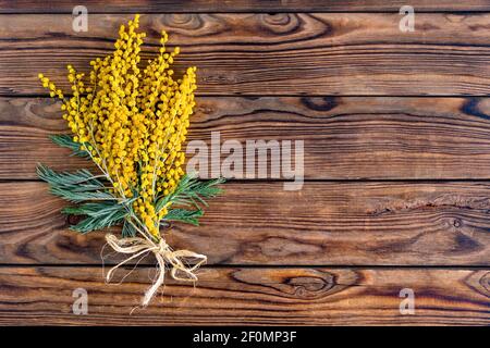 Fleurs mimosa jaunes sur fond de bois brun vintage gros plan plat composition avec espace vide pour le texte, concept de carte de vœux, modèle publicitaire, couverture et papier d'emballage Banque D'Images