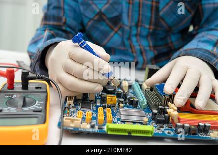 technicien réparant l'intérieur du disque dur à l'aide d'un fer à souder. Circuit intégré. Concept de données, de matériel, de technicien et de technologie. Banque D'Images