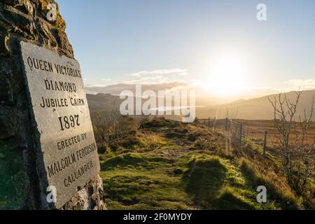 1897 Queen Victoria Diamond Jubilee cairn plaque avec coucher de soleil sur la ligne d'horizon ; érigé par Malcolm Ferguson à Callander, Écosse - Royaume-Uni Banque D'Images