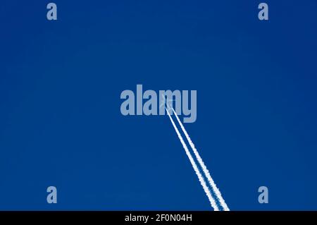 Avion à réaction dans le ciel bleu avec des pistes blanches au-dessus du village de Nisovo, Bulgarie Banque D'Images