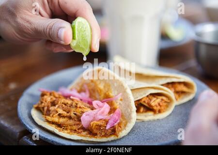 gros plan homme méconnaissable mettant du citron dans ses tacos à l'oignon rouge Banque D'Images