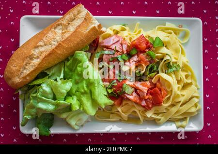 Avec salade de pâtes, jambon et légumes en plaque blanche Banque D'Images