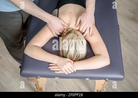 Thérapeute offrant un massage du cou et du dos à la patiente clinique Banque D'Images