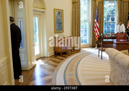 L'assistant du président pour les affaires législatives Phil Schiliro regarde la fenêtre pendant que le président Barack Obama parle au téléphone dans le bureau ovale octobre 8 2009. Banque D'Images