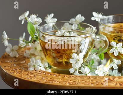 Thé de fleur de cerisier dans une tasse de verre avec des branches florales en fleur à proximité, la boisson saine de fines herbes est bon pour la peau et le coeur, riche en antioxydants et l'esse Banque D'Images