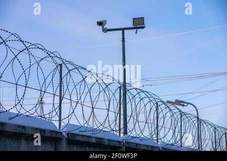 Une clôture barbelée à pointe effilée en fil de rasoir enroulée sur le dessus du le mur protège des prisonniers et des criminels en prison et de entrée dans la zone restreinte ou Banque D'Images