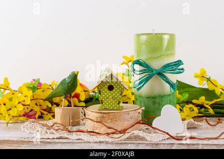 Un arrangement de printemps de fleurs avec une bougie, un oiseau en bois et un birdhouse. Banque D'Images