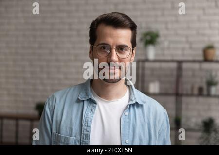 Portrait de tête d'un homme millénaire confiant portant des lunettes posé à l'intérieur Banque D'Images