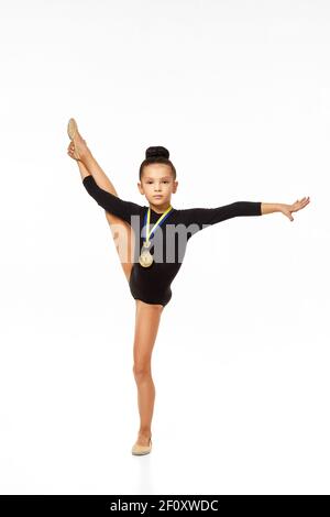 petite fille de gymnaste en body noir avec médaille d'or isolée sur fond blanc Banque D'Images