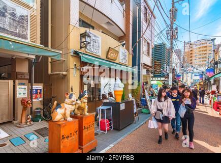 tokyo, japon - avril 05 2019 : paire de deux statues en bois de maneki-neko chats japonais avec un paw levé pour faire du shopping aux jeunes touristes Banque D'Images