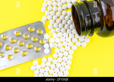 Beaucoup de capsules de gel de vitamine D3 2000 UI et de vitamine Comprimés K2 sur fond jaune Banque D'Images