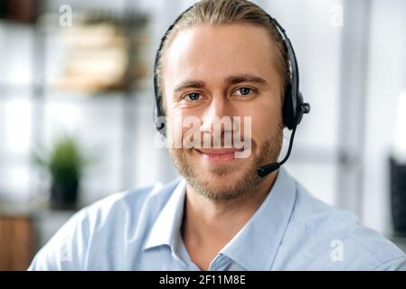 Portrait en gros plan d'un opérateur de centre d'appels ou d'un chef d'entreprise à barbe attrayant. Homme d'affaires caucasien dans le casque et le maillot formel regarde la caméra et souriant amical Banque D'Images