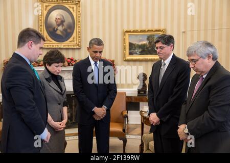 Le président Barack Obama fait une pause au cours d'une réunion pour observer un moment de silence dans le Bureau ovale à 9 h 30 le 21 2012 décembre en souvenir des 20 enfants et six adultes tués dans le tir de l'école élémentaire Sandy Hook à Newtown, au Connecticut, le 14 décembre. Parmi les membres du président de gauche, on trouve le directeur des communications, Dan Pfeiffer, la conseillère principale, Valerie Jarrett, le chef d'état-major, Jack Lew, et le conseiller de Pete Rouse auprès du président. Banque D'Images