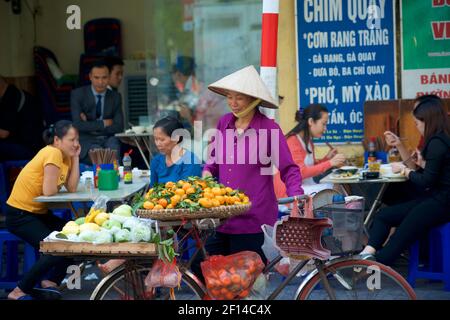 Vie de rue vietnamienne. Vendeur de fruits itinérant avec vélo en plus du café en bord de route. Hanoï, Vietnam Banque D'Images