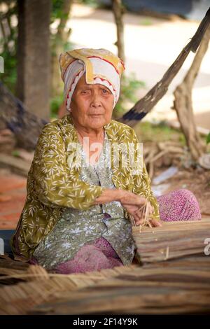 Femme vietnamienne âgée qui plâte des feuilles de plam, île de Tân Phong, delta du Mékong, Vietnam Banque D'Images