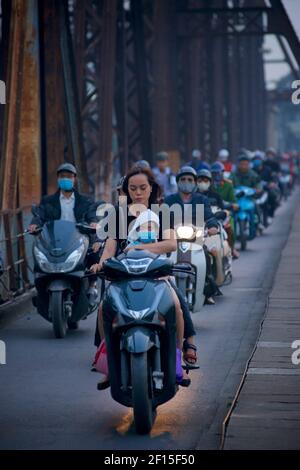 Des navetteurs de la ville vietnamienne sur des motos traversant le pont historique de long Bien, Hanoi, Vietnam. Banque D'Images