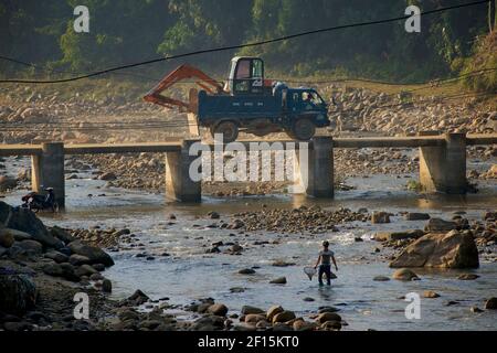 Pont sur la rivière, Ta Van, près de Sapa, province Lao Cai, nord du Vietnam. Bulldozer traversant le pont; homme avec filet de pêche dans la rivière ci-dessous. Banque D'Images