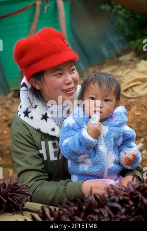 Jeune mère vietnamienne avec son jeune enfant. Vente de piments rouges séchés au marché CAN Cau, Vietnam, province Lao Cai, Vietnam Banque D'Images