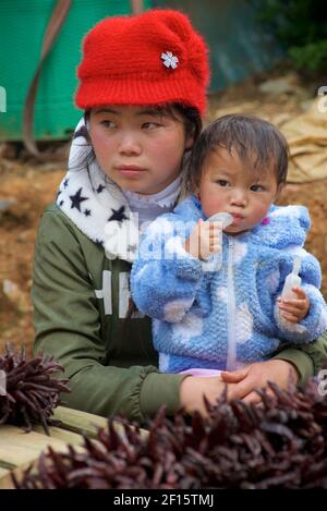 Jeune mère vietnamienne avec son jeune enfant. Vente de piments rouges séchés au marché CAN Cau, Vietnam, province Lao Cai, Vietnam Banque D'Images