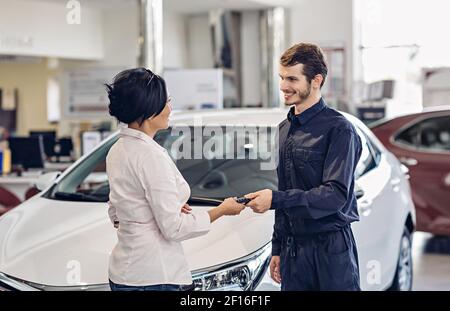 Scène de centre de service de voiture. Le mécanicien qui donne la clé de voiture au client Banque D'Images