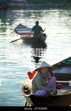 Une femme vietnamienne attend un client pour faire un court voyage en bateau le long des canaux et de la rivière Thu bon, Hoi an, Vietnam Banque D'Images