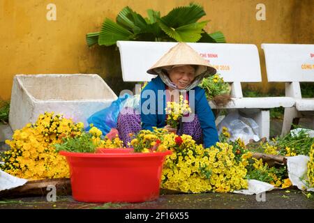 Vendeur de fleurs vietnamiennes en chapeau conique distinctif. Marché Hoi an, Vietnam Banque D'Images