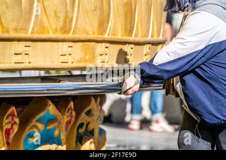 Mains d'un touriste tournant la prière bouddhiste tibétaine géante Roue du temple Dafo dans la vieille ville de Dukezong à Shangri-la Yunnan Chine Banque D'Images