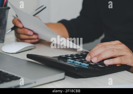 Homme d'affaires utilisant la calculatrice à un bureau. Finance d'entreprise, impôts et concepts d'investissement. Banque D'Images