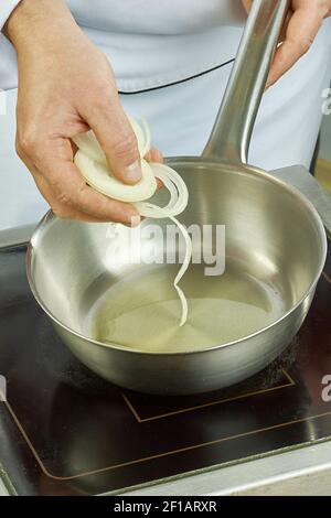 Faites cuire les frites en rondelles d'oignon blanc dans une série de casseroles pleine recettes de cuisine Banque D'Images