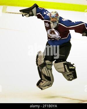 As Colorado Avalanche goalie Patrick Roy looks on in the crease in the  background, Boston Bruins left winger P.J., Axelsson, center, slides across  the ice after being tripped up by Colorado Avalanche