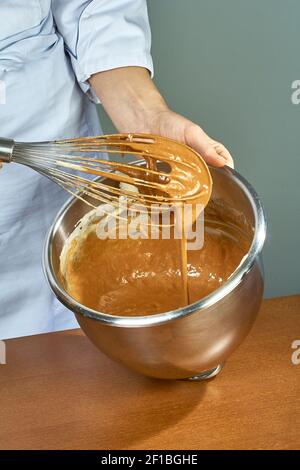Le chef fouette la crème jaune dans un bol à la main pour faire des cheeseckes Banque D'Images