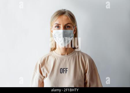 Portrait en gros plan sur un fond pâle d'une femme caucasienne dans un masque médical protecteur. Banque D'Images