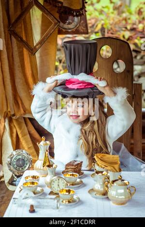 Un peu de belle fille holding hat cylindre avec les oreilles comme un lapin sur la tête à la table Banque D'Images