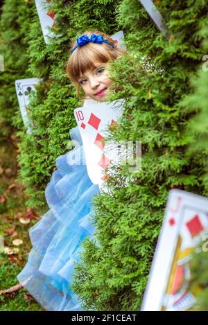 Une petite fille magnifique dans une longue robe bleue à la recherche de sous les sapins Banque D'Images