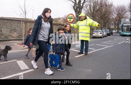 Brighton UK 8 mars 2021 - l'homme Lollipop Simon Moss accueille les enfants de retour à l'école primaire St Luke à Brighton ce matin, car les restrictions de verrouillage du gouvernement en Angleterre commencent à être assouplies . Les écoles et les collèges sont rouverts à tous les étudiants aujourd'hui dans toute l'Angleterre : crédit Simon Dack / Alamy Live News Banque D'Images