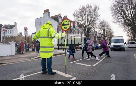 Brighton UK 8 mars 2021 - l'homme Lollipop Simon Moss accueille les enfants de retour à l'école primaire St Luke à Brighton ce matin, car les restrictions de verrouillage du gouvernement en Angleterre commencent à être assouplies . Les écoles et les collèges sont rouverts à tous les étudiants aujourd'hui dans toute l'Angleterre : crédit Simon Dack / Alamy Live News Banque D'Images